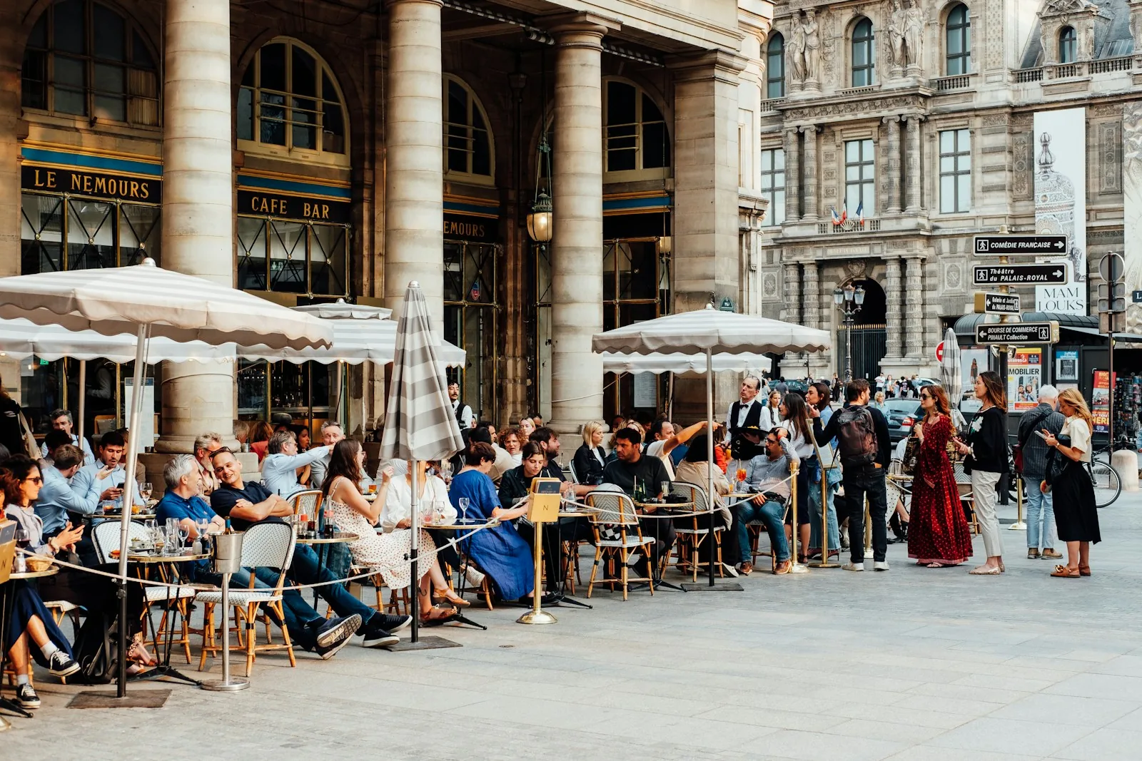 Sunlit café terrace with woven chairs and white parasols in Paris