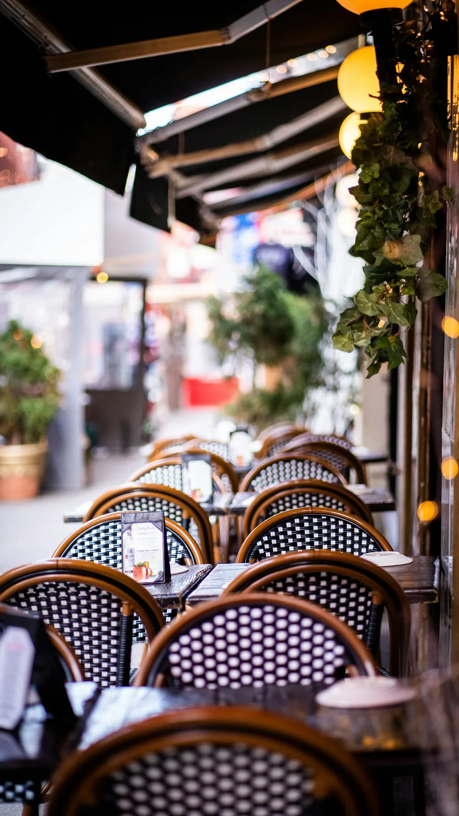 Outdoor restaurant tables and woven chairs along a sidewalk in Little Italy, New York