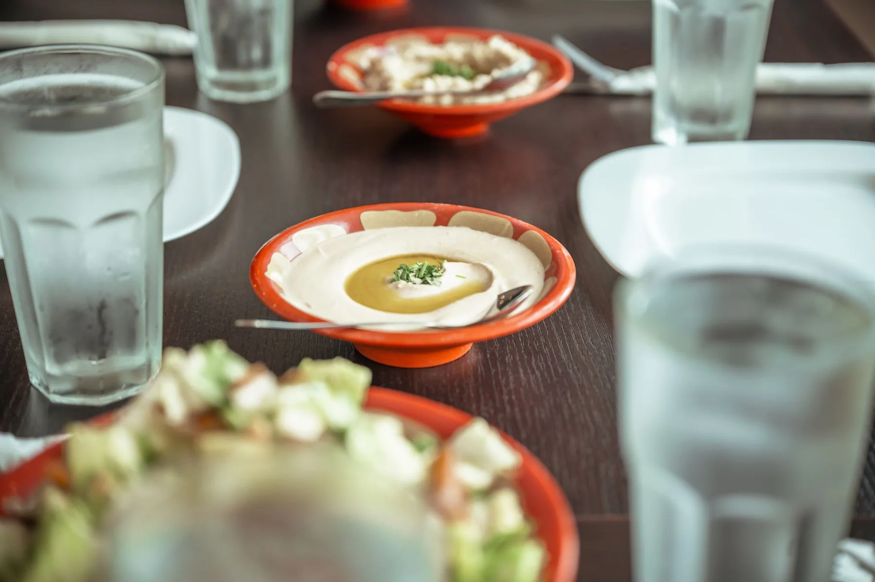 Chilled water, hummus and salad shared at a restaurant table